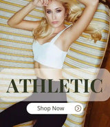 LOVEMI woman lying on a striped couch in an athletic outfit consisting of a white sports bra and black leggings, promoting the LOVEMI athletic wear collection.